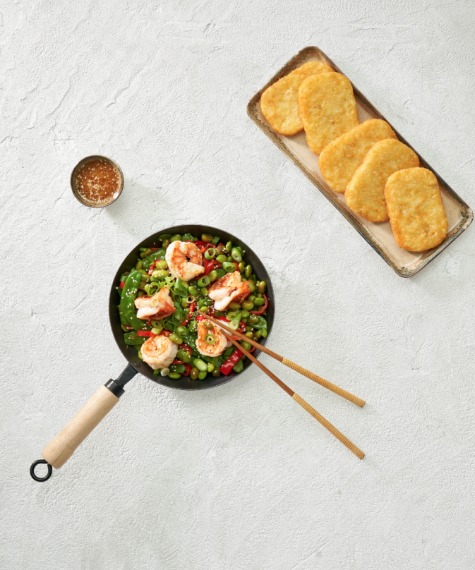 Rectangular hash browns with stir-fry with edamame beans, bell peppers, snow peas, and scallions