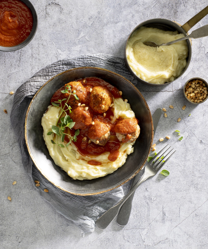 Pure mashed potatoes with meatballs in tomato sauce